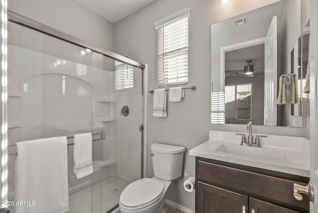 bathroom featuring vanity, a shower with shower door, and toilet