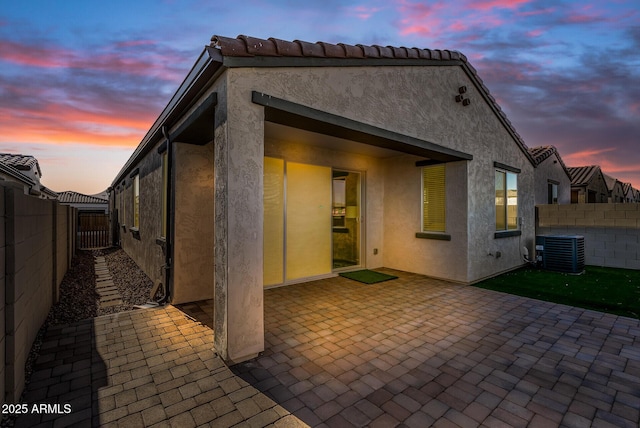 back house at dusk featuring a patio and central AC