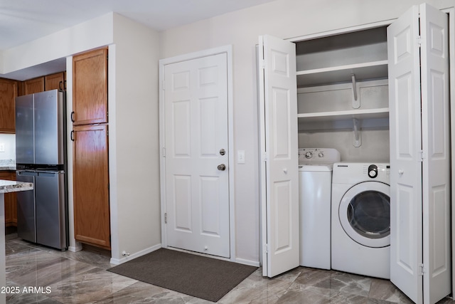 clothes washing area with laundry area, baseboards, marble finish floor, and washing machine and dryer