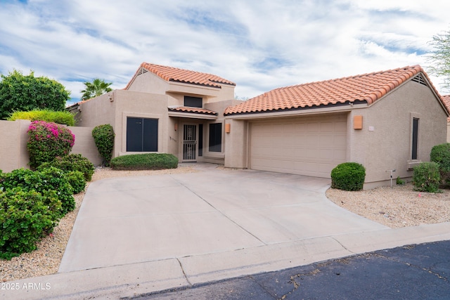 mediterranean / spanish house with a garage, fence, stucco siding, driveway, and a tile roof