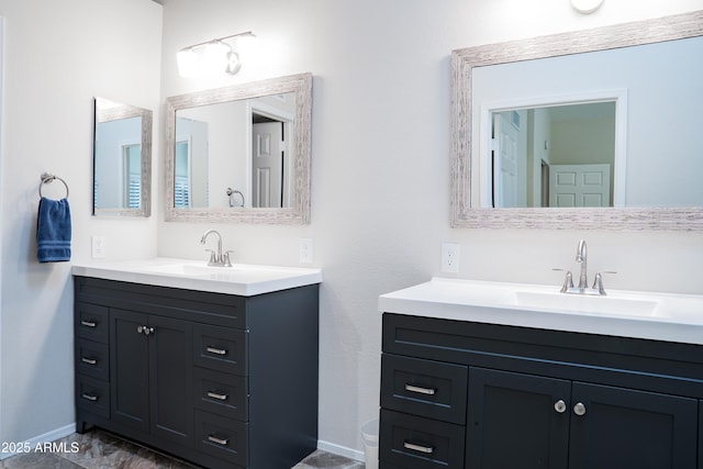 bathroom featuring a sink, baseboards, and two vanities