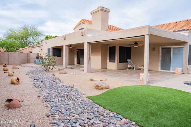 rear view of house featuring ceiling fan, stucco siding, a tiled roof, and fence