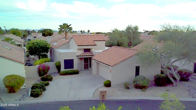 mediterranean / spanish home with a tiled roof, an attached garage, driveway, and stucco siding