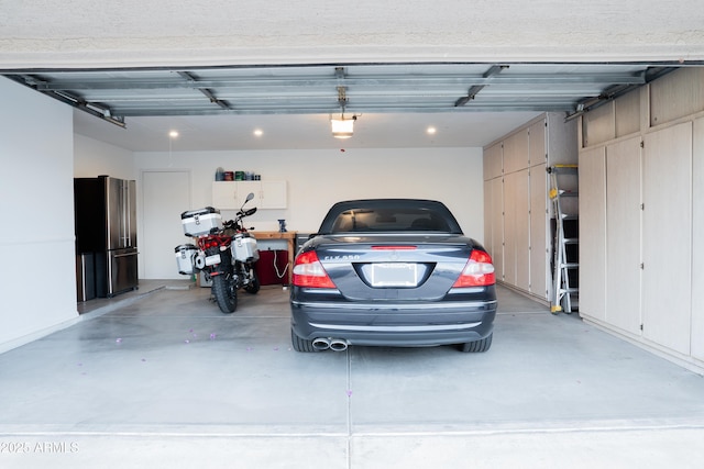 garage featuring a garage door opener, freestanding refrigerator, and recessed lighting