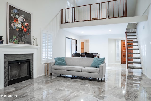 living room with a tiled fireplace, marble finish floor, stairs, baseboards, and a towering ceiling