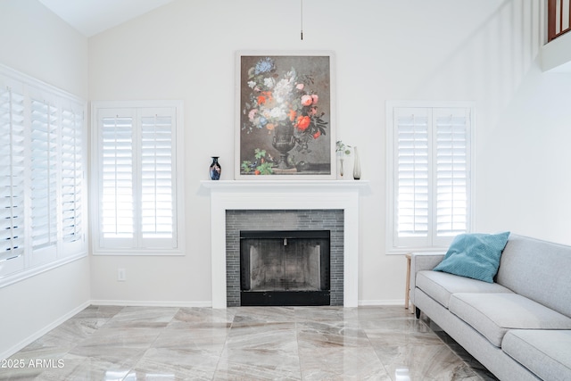 living room featuring a tiled fireplace, plenty of natural light, vaulted ceiling, and marble finish floor