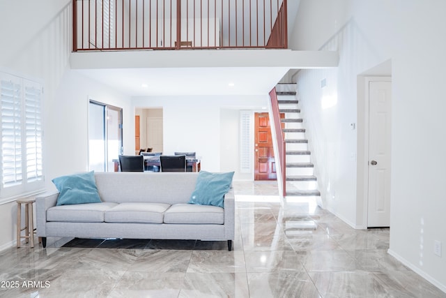 living area with stairway, a towering ceiling, baseboards, and marble finish floor