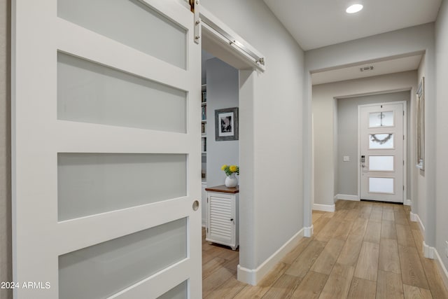 hallway featuring light wood-type flooring and a barn door