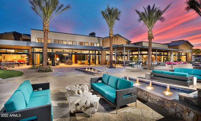 pool at dusk featuring an outdoor living space with a fire pit and a patio area