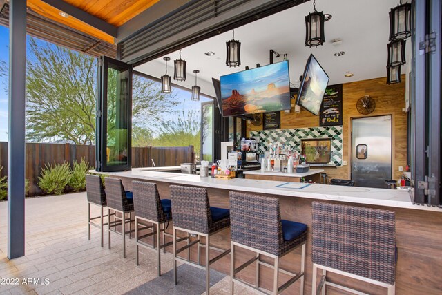 kitchen featuring a kitchen breakfast bar, wooden walls, kitchen peninsula, and decorative light fixtures