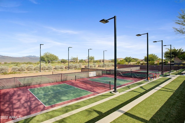 view of tennis court with a mountain view and a yard