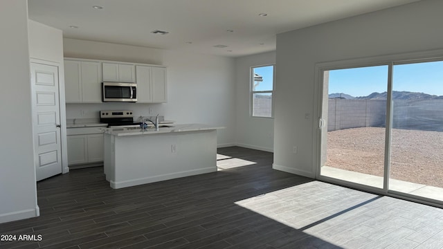 kitchen featuring a mountain view, a kitchen island with sink, sink, white cabinets, and white range with electric cooktop