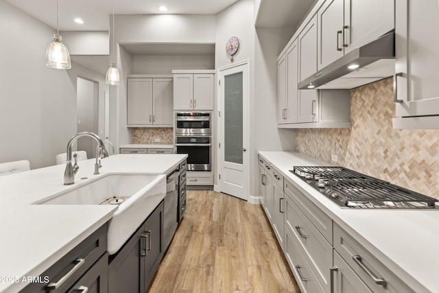 kitchen with backsplash, sink, decorative light fixtures, and appliances with stainless steel finishes