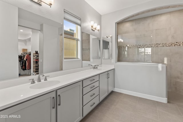 bathroom with tile patterned flooring, vanity, and tiled shower