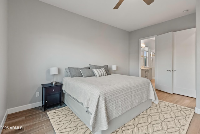 bedroom with connected bathroom, hardwood / wood-style flooring, and ceiling fan