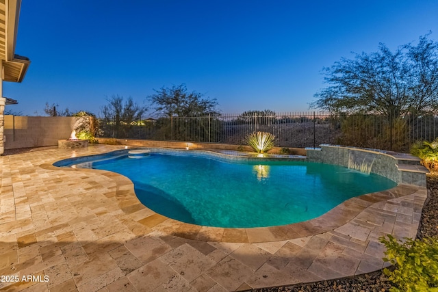 pool at dusk featuring pool water feature and a patio area