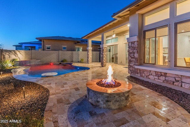 patio terrace at dusk featuring a fenced in pool and an outdoor fire pit