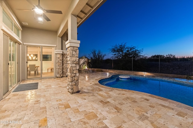 pool at dusk featuring ceiling fan and a patio