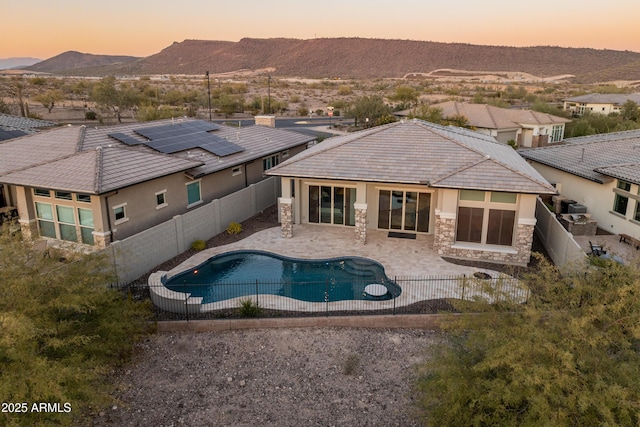 pool at dusk with a mountain view and a patio area