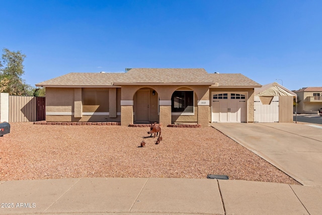 ranch-style home with concrete driveway, an attached garage, a gate, and stucco siding