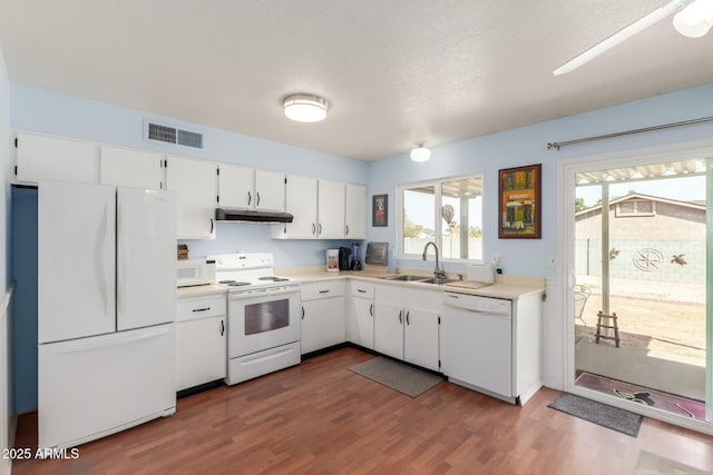 kitchen with light countertops, visible vents, a sink, white appliances, and under cabinet range hood