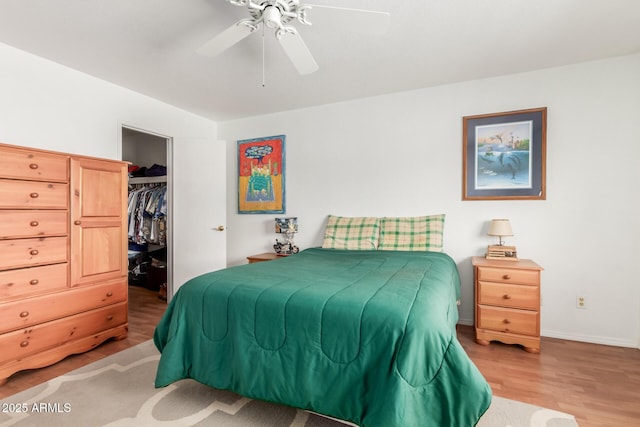 bedroom featuring ceiling fan, a closet, a spacious closet, and wood finished floors