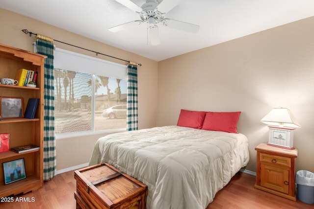 bedroom with light wood finished floors, a ceiling fan, and baseboards