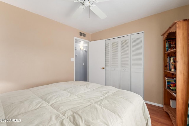 bedroom with ceiling fan, a closet, visible vents, and wood finished floors