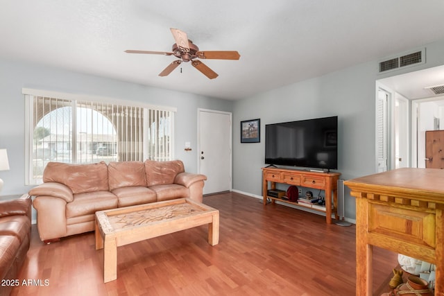 living area featuring a ceiling fan, baseboards, visible vents, and wood finished floors