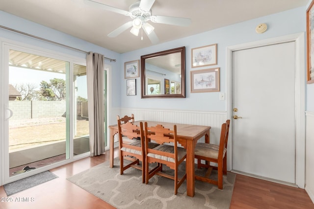 dining area featuring a wainscoted wall, a ceiling fan, and wood finished floors