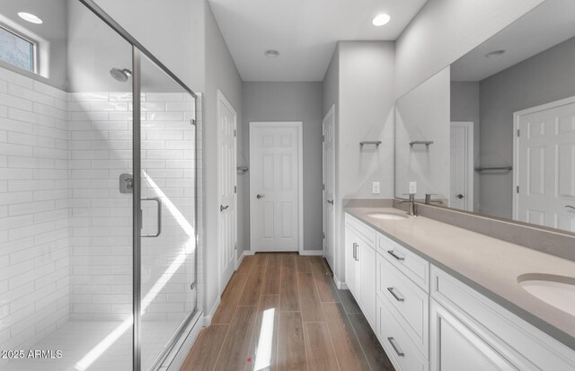 17809 W Getty Dr, Goodyear, AZ 85338 - bathroom featuring a sink, wood finished floors, a stall shower, double vanity, and baseboards