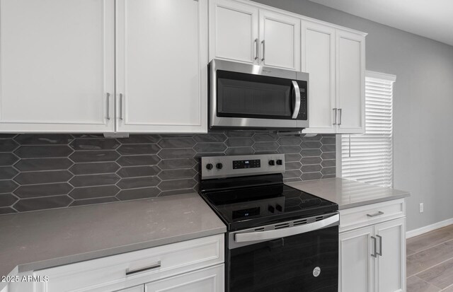 17809 W Getty Dr, Goodyear, AZ 85338 - kitchen with light wood-type flooring, backsplash, white cabinetry, light countertops, and appliances with stainless steel finishes