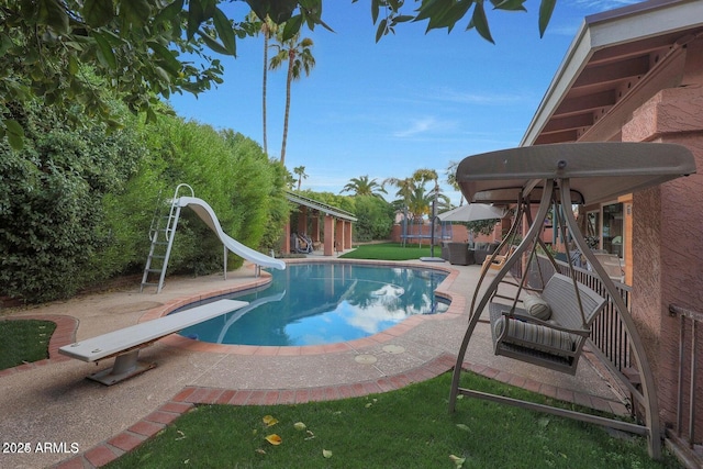 view of pool featuring a diving board, a yard, a patio, and a water slide