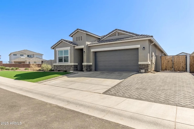 view of front facade featuring an attached garage, stone siding, driveway, a gate, and stucco siding