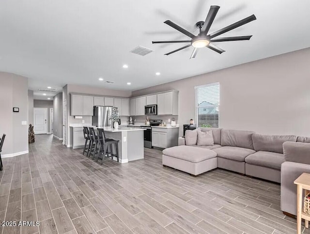 living room with wood finish floors, recessed lighting, visible vents, ceiling fan, and baseboards