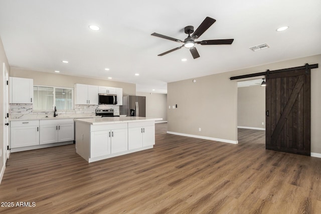 13805 N 31st Ave, Phoenix, AZ 85053 - kitchen featuring appliances with stainless steel finishes, a barn door, a ceiling fan, a center island, and white cabinetry