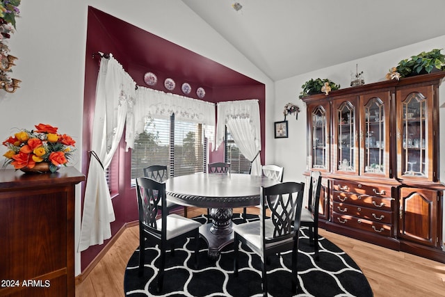 dining room featuring light wood-type flooring and vaulted ceiling