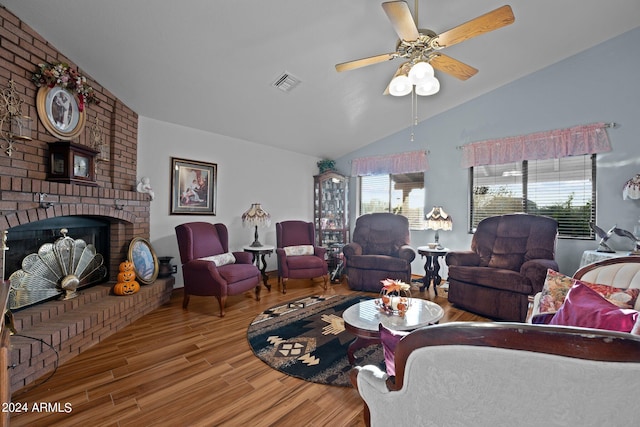 living room featuring ceiling fan, hardwood / wood-style flooring, a fireplace, and vaulted ceiling