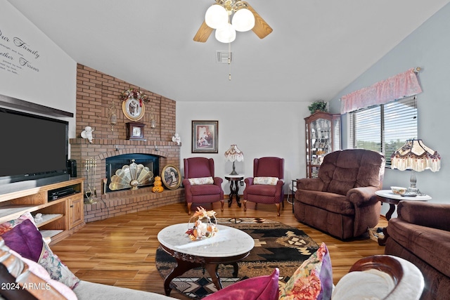 living room featuring lofted ceiling, hardwood / wood-style floors, ceiling fan, and a brick fireplace