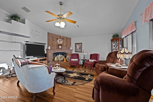 living room featuring a brick fireplace, lofted ceiling, wood-type flooring, and ceiling fan