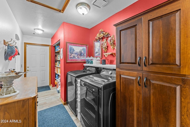 clothes washing area with cabinets, separate washer and dryer, a textured ceiling, and light wood-type flooring