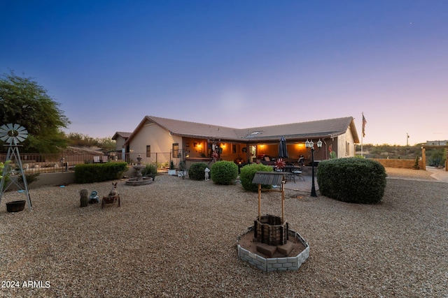 back house at dusk featuring a patio area