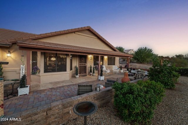 back house at dusk featuring an outdoor hangout area and a patio