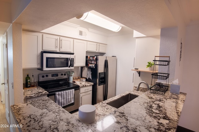 kitchen with white cabinets, sink, appliances with stainless steel finishes, kitchen peninsula, and light stone countertops