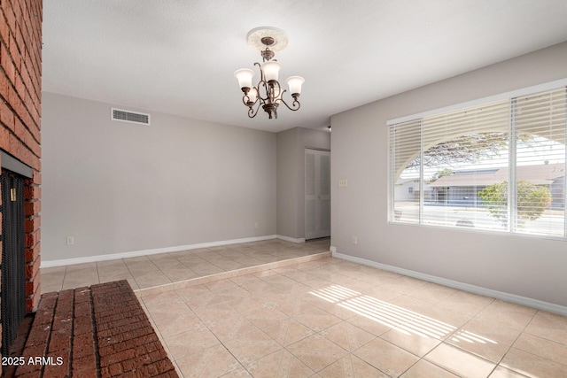 tiled spare room with an inviting chandelier