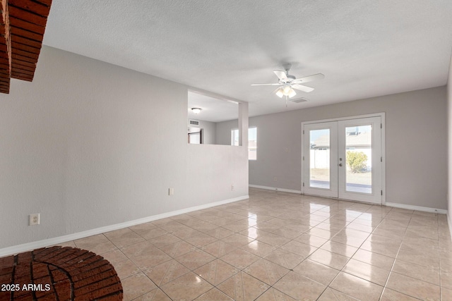 tiled empty room featuring ceiling fan, a textured ceiling, a wealth of natural light, and french doors