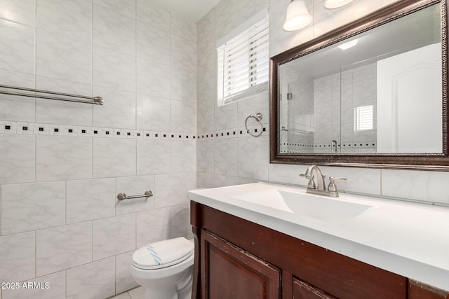 bathroom with vanity, tile walls, and toilet