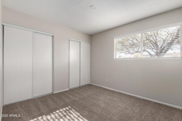 unfurnished bedroom featuring carpet and multiple closets