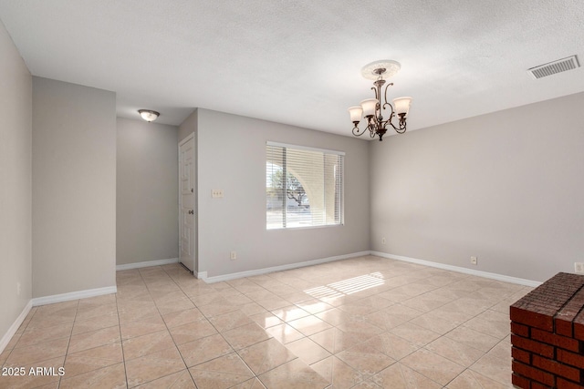 tiled empty room with a chandelier and a textured ceiling