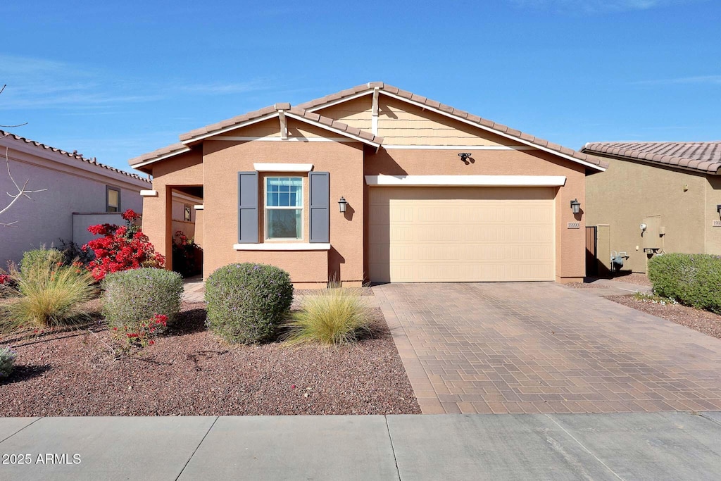 view of front of property with a tiled roof, decorative driveway, an attached garage, and stucco siding